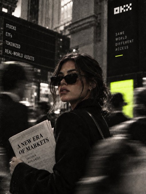 A woman wearing sunglasses and a dark jacket stands in a crowded urban setting holding a newspaper titled 'A NEW ERA OF MARKETS,' with an OKX billboard reading 'STOCKS, ETFs, TOKENIZED REAL-WORLD ASSETS' and 'SAME WORLD DIFFERENT ACCESS' visible in the background.