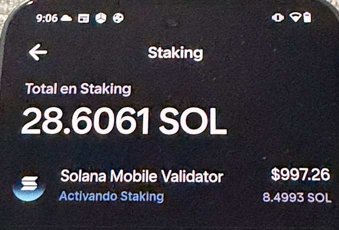 A photograph of a smartphone screen showing a Solana staking interface displaying 'Total en Staking: 28.6061 SOL' with a 'Solana Mobile Validator' entry showing $997.26 and 8.4993 SOL, labeled 'Activando Staking'.