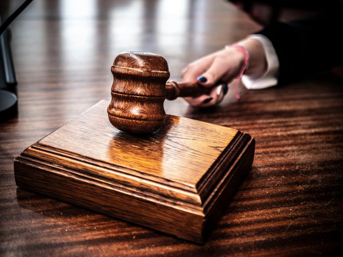 A wooden gavel rests on a matching sounding block with a hand reaching toward it on a polished wooden surface.

The image relates to the post as the gavel symbolizes the legal action taken by the traders who are suing Polymarket over the disputed resolution of their Bitcoin market.