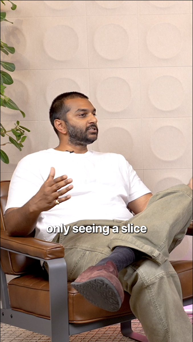 A man in a white t-shirt and olive pants sits in a brown leather chair, gesturing while speaking, with the caption "only seeing a slice" overlaid on the image, reflecting his point about crypto's untapped potential for the West.