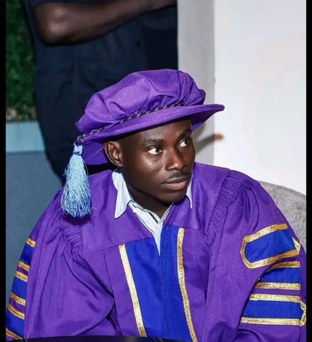 A young man wearing a purple academic gown and matching cap with a light blue tassel, looking to the side.