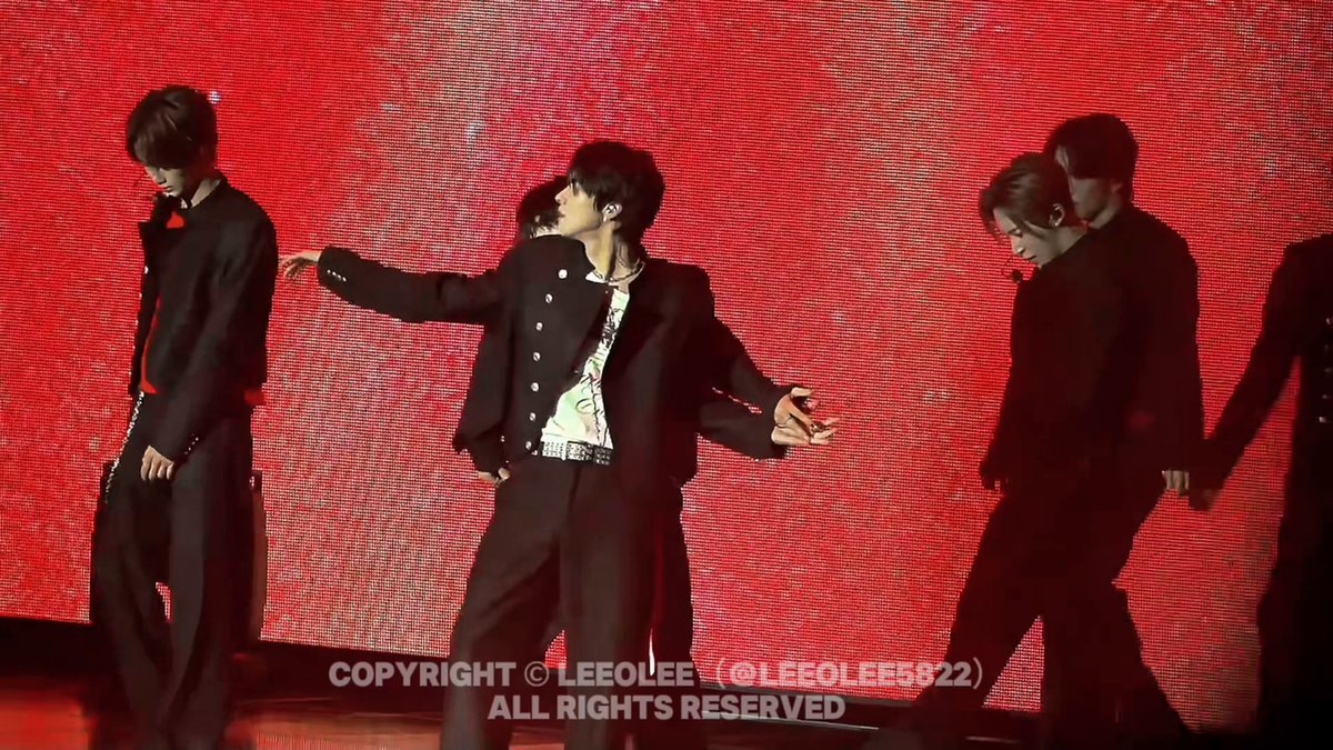 The image features a group of people dressed in black clothing, with one person wearing a suit and another person wearing a tuxedo. They are standing together against a red background, which appears to be part of a stage or performance setting. The caption for the image reads "I'M JUST WORSING IT, IT'S SO GOOD, OUR RAW flame #ALPHADRIVEONE #ALD1". This suggests that they might be performers on stage, possibly in a musical or theatrical context.