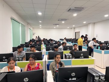 A group of people, mostly young adults, are seated at computer workstations in a brightly lit training room or computer lab, with several HP monitors visible in the foreground. The image aligns with the post's caption, showing Shardeum's team engaging with "the next generation of builders" during a workshop stop on the #POCIndiaOnChainTour in Gwalior.