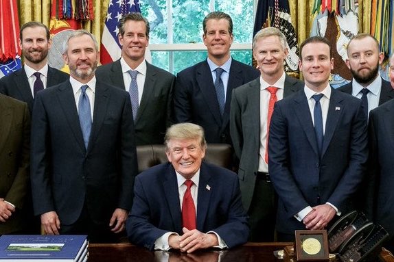 The image shows President Donald Trump seated at the Resolute Desk in the Oval Office, surrounded by a group of men in business suits, with the caption "representing for the XRP Family ✅" suggesting this is a White House meeting related to the XRP/cryptocurrency community, possibly featuring Ripple-affiliated individuals meeting with the President.

A concise caption would be: "President Donald Trump meets with a group of businessmen, including Ripple/XRP representatives, in the Oval Office of the White House."