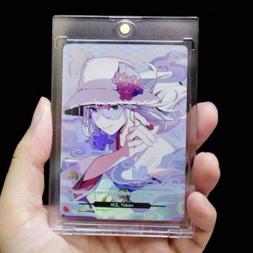 A hand holds up an Azuki TCG (trading card game) card featuring an anime-style character in a white hat adorned with purple flowers, with the name "RED Token" visible at the bottom. The image illustrates how Azuki's NFT brand is expanding into new mediums like trading card games, bringing its distinctive art style to broader audiences beyond the Web3 space.