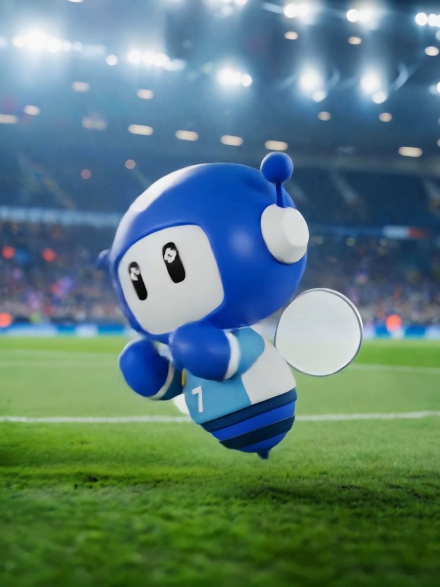 An adorable blue robot mascot with the number "1" on its jersey appears to be running or flying across a soccer field in a stadium, captured mid-action with bright stadium lights overhead. The mascot's energetic pose reflects the celebratory spirit of the post about lifting a trophy one final time before retirement.