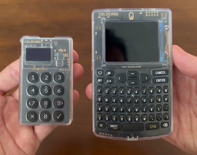 Two hands hold transparent 'COLDCARD' hardware cryptocurrency wallets, one a compact Mk4 model with a numeric keypad and the other a larger Q model featuring a full QWERTY keyboard.
