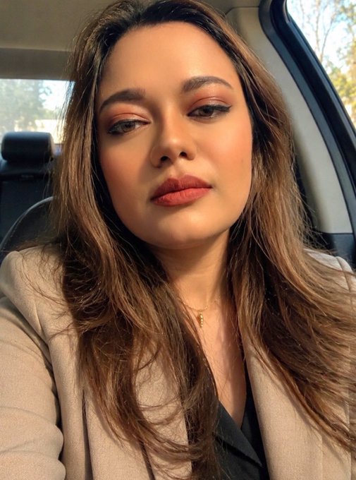A woman with long brown hair, smoky eye makeup, and matte lipstick takes a selfie inside a car. She pairs her polished look with a caption about gearing up for a Monday grind at Quip Network, promoting the crypto ticker $QUIP as a timely investment in quantum computing.