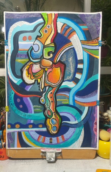 A vibrant, colorful abstract painting on an easel featuring swirling patterns in blue, purple, orange, and green hues, with a yellow object visible in the foreground.
