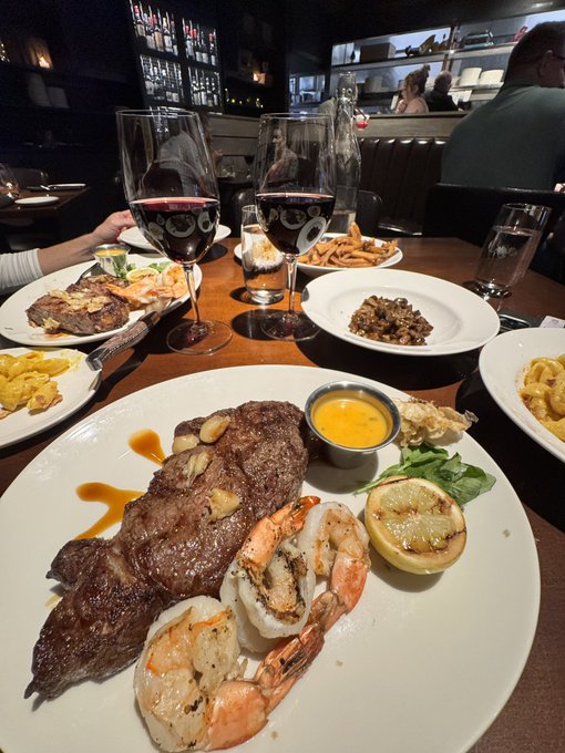 A delicious surf and turf dinner featuring steak and shrimp with roasted lemon is being paid for, perhaps by someone shilling a newly launched community-based crypto token in the comments.