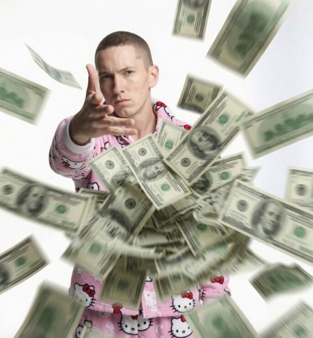 A man wearing pink Hello Kitty pajamas reaches toward the camera as US dollar bills fly through the air around him.