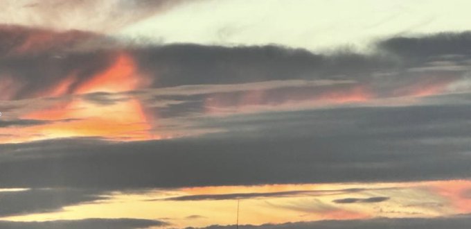 A vibrant sunset sky filled with streaks of orange, pink, and yellow light piercing through dark horizontal cloud bands. The image pairs with a post referencing a networked.art link, likely serving as the visual artwork for the digital piece or token being shared.