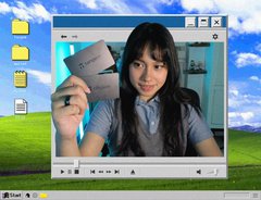 A woman with dark hair is smiling at the camera while holding up a silver "Tangem" card, shown within a Windows Media Player window on the classic Windows XP desktop. The image appears to be a screenshot capturing her celebrating the completion of a cinematic short film created for Tangem.