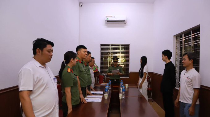 The image shows a group of people standing around a long table, with some men wearing uniforms and others dressed casually. The scene appears to be taking place inside an office or a room with white walls. There are several chairs placed around the table, indicating that this gathering might involve discussions or meetings related to work-related matters.

The post includes text such as "CÔNG AN LÀO CAI TRIỆT PHÁ ĐƯỜNG DÂY RỬA tiền Công an tỉnh Lào Cai vừa khởi tố và bắt tạm giam", which suggests that the image might be related to a work-related event or gathering. The presence of water bottles on the table also indicates that refreshments are being provided for the attendees during this meeting.