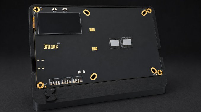 A sleek black Bitaxe mining device is displayed against a dark background, featuring gold accents and the "Bitaxe" logo alongside a small LCD screen, connection ports labeled "Reset" and "WiFi," and test points marked "TP08," "TP07," and "TP05." The compact hardware, likely a new Bitcoin mining product, ties into the promotional post about the upcoming Naja Duo launch.
