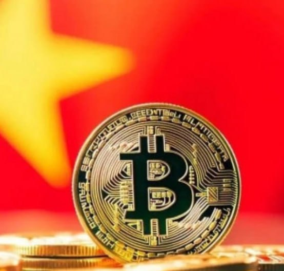 A physical Bitcoin token is displayed against the backdrop of the Chinese flag, with the coin's inscriptions including "BITCOIN DIGITAL DECENTRALIZED PEER TO PEER" and "VIRES IN NUMERIS" clearly visible. The image symbolizes the intersection of cryptocurrency and the Chinese market, relating to Vietnam's new personal income tax law imposing a 0.1% tax on digital asset transfers effective July 1, 2026.
