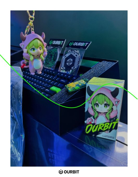 The image showcases a vibrant display at Token2049 Day 2 featuring the "OURBIT" brand, including a green-haired anime mascot figure, branded keychains, and promotional boxes arranged on a keyboard-themed display, tying into "The Green Exchange" party theme with the signature green color palette throughout.