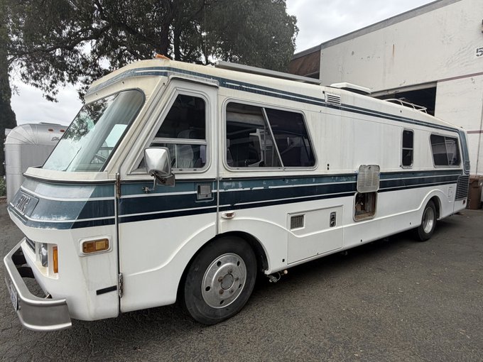 A vintage white and teal motorhome parked outdoors, with the word 'Airstream' partially visible on the front.