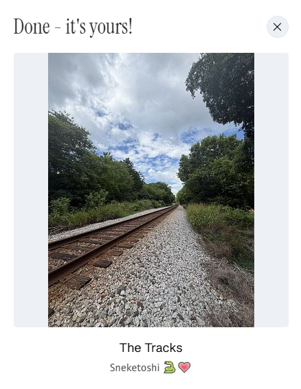 A confirmation screen showing a completed post titled "The Tracks" from user Snekatoshi with a snake emoji, featuring a photo of railroad tracks extending into the distance under a cloudy sky.
