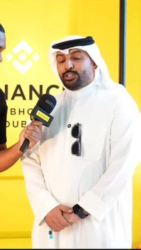A man in traditional Arab attire being interviewed by someone holding a Bloomberg microphone at the Binance Blockchain Dubai event.