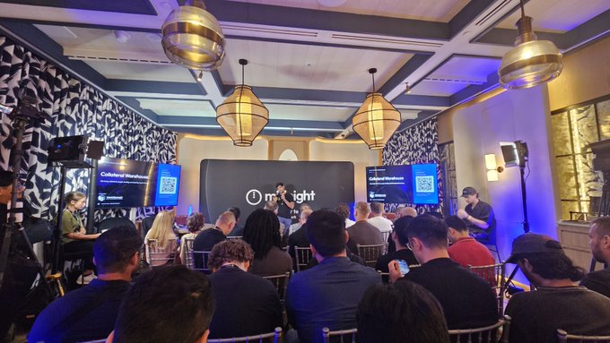 An audience gathers at an indoor event where two presenters stand on stage beside screens displaying "Cultivated Warehouse" with QR codes, under a banner featuring the "Midnight" logo and globe icon. The setup aligns with the post's emphasis on innovation, showcasing builders and developers engaged in a presentation about emerging tech within the Midnight Network community.
