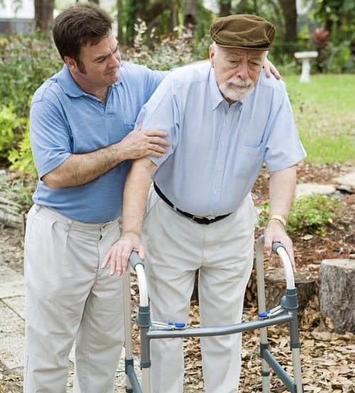 A younger man supports an elderly man wearing a flat cap as he uses a walker to navigate a garden path, illustrating the post's humorous reflection on how times have changed—suggesting the older man's generation struggled to even walk, let alone adapt to modern crypto trends like selling JPEGs for six figures in Ethereum.