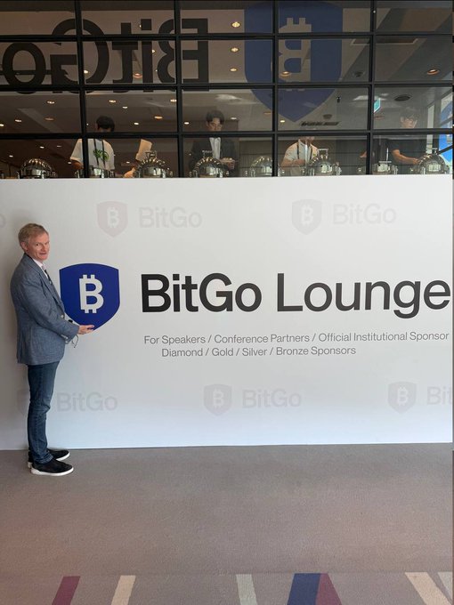 A man poses next to a "BitGo Lounge" banner designating the area for Speakers, Conference Partners, and Institutional Sponsors, illustrating the post's announcement that the BitGo lounge is open.