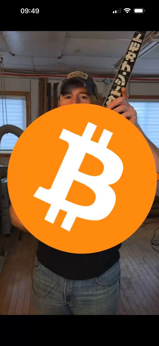 The image shows a man standing against a wall with his face partially obscured by an orange circle that displays the Bitcoin symbol. The man appears to be wearing a black shirt and blue jeans. The caption of the image reads "RESEARCH $DOG I hope this gets to hard headed peeps like me. I've been around bitcoin since 2011 but never got in until 2016. Bought bitcoin all the time then sold, moved, took time off".