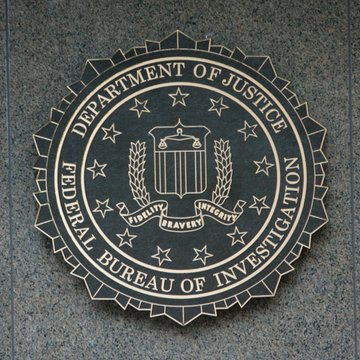 The seal of the U.S. Department of Justice and Federal Bureau of Investigation is displayed on a stone surface, featuring an eagle, shield, and stars with the motto "Fidelity, Bravery, Integrity." The image relates to the post as it represents the federal agencies, including FinCEN, involved in investigating and reporting on the $12.7 billion in suspicious crypto activity linked to overseas "pig butchering" scam networks.