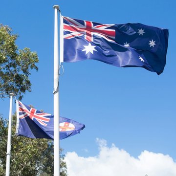 The Australian flag waves against a clear blue sky, symbolizing the nation as AUSTRAC intensifies its regulatory crackdown, canceling, suspending, or refusing to renew 45 crypto and remittance registrations in the past year.