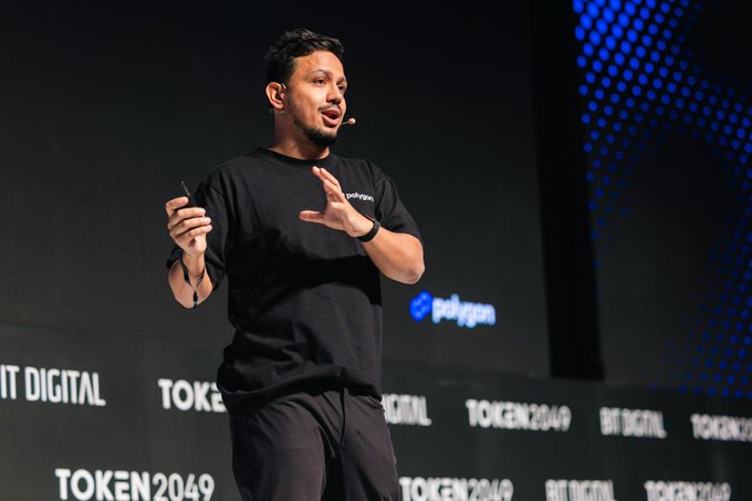 A man wearing a black "Polygon" t-shirt speaks passionately on stage with hand gestures, captured during a presentation at TOKEN2049, as indicated by the visible "TOKEN2049," "BT DIGITAL," and "polygon" branding on the backdrop.