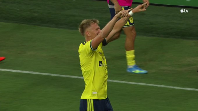 A Nashville player in a yellow jersey celebrates with arms raised on the pitch during the match against Inter Miami, contributing to his team's dominant 4-1 lead over Messi and company in the 82nd minute.