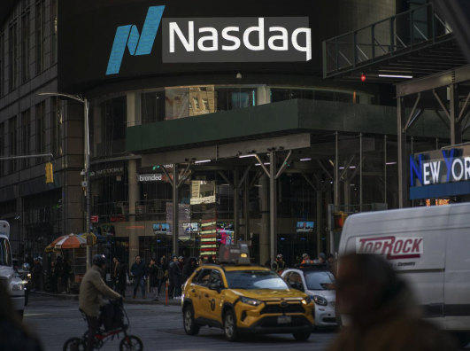 A bustling city street scene features a large illuminated NASDAQ sign atop a building, with a yellow taxi, a TopRock van, and a cyclist navigating the road below. The NASDAQ branding ties directly to the post about Nasdaq's $100 million investment in Kraken (Payward), suggesting early investment positioning in the crypto exchange.