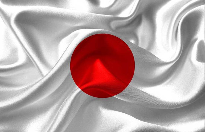 The flag of Japan, featuring a red circle on a white background, appears to be made of flowing silk fabric.