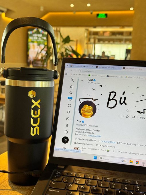 A black SCEX-branded tumbler sits next to a laptop displaying the @SVCut555 Twitter profile, captured at the Vietnam RWA Summit 2026. The setup highlights the local exchange's presence at the event, aligning with the post's promotion of SCEX's leaderboard rewards program offering up to 200 million VND in prizes.