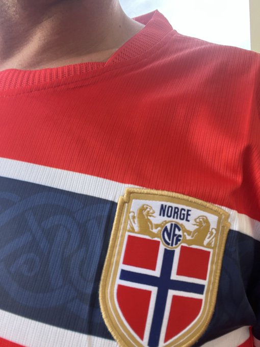A person wears a red, white, and blue sports jersey featuring the "NORGE" crest with two lions and the Norwegian flag shield. The jersey matches the post's reference to Norway ("Norge"), likely being a supporter's kit for the Norwegian national team.