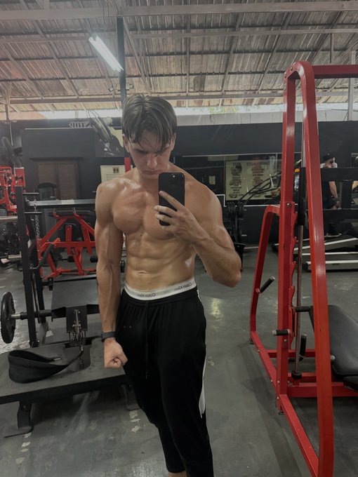 A young man takes a mirror selfie at the gym, displaying a defined and lean physique. The image, accompanying a German post about the true sources of lasting success (mind and body over money, bitcoin, or social media attention), visually reinforces the message that physical health and mental strength are what ultimately matter, regardless of wealth or popularity.