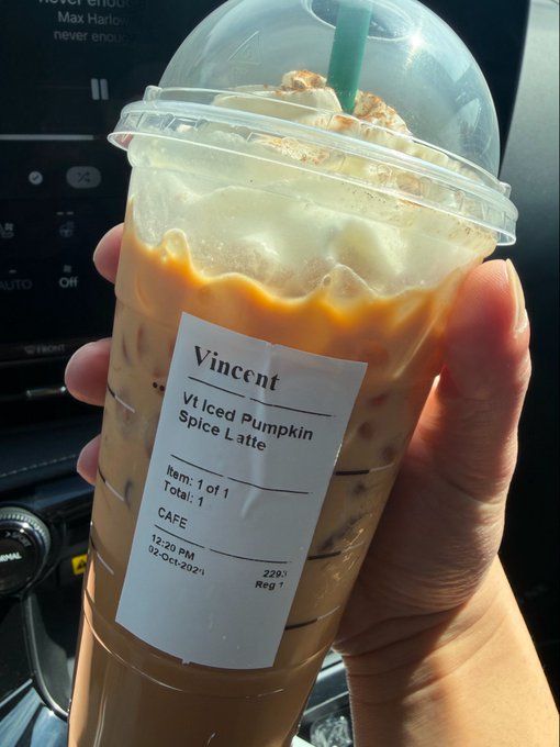 A hand holds a Starbucks iced drink with a receipt labeled 'Vt Iced Pumpkin Spice Latte' for Vincent, ordered at 12:29 PM on 12-Oct-2021.