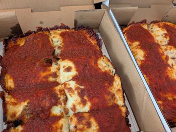 Two Detroit-style deep dish pizzas with thick, crispy golden crusts and rich tomato sauce topping sit in open delivery boxes, fitting the post's celebration of a Bitcoin transaction at a local pizzeria. No visible text or branding appears in the image, but the hearty, square-cut slices match the description of "the BEST Detroit-style deep dish pizza" paid for in sats.