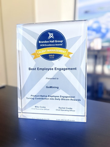 A Brenton Hall Group HCM Excellence Awards trophy sits on a desk, honoring GoMining for "Best Employee Engagement" with a Gold Talent Management 2025 award, presented by Mike Cooke and Rachel Cooke for "Product-Native Employee Engagement: Turning Contribution into Daily Bitcoin Rewards"—visually reinforcing the post's message about rewarding employees with Bitcoin miners rather than traditional bonuses.