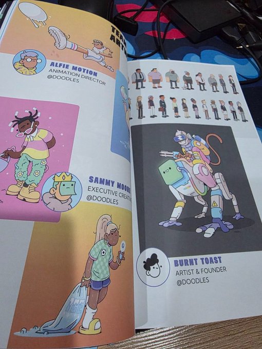 An open book or magazine displaying character designs, including 'ALFIE MOTION - ANIMATION DIRECTOR @DOODLES' and 'SAMMY MOON - EXECUTIVE CREATIVE @DOODLES'.