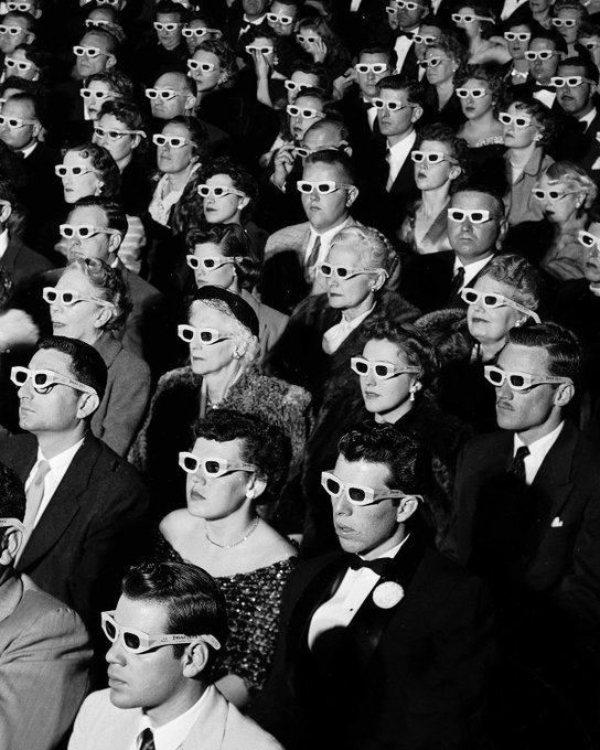 A black-and-white vintage photograph shows a packed movie theater audience wearing 3D glasses, all staring intently forward as they watch a screening. The image pairs with the caption "Eyes forward. Agents incoming: okx.ai," evoking a similar sense of collective, focused anticipation for the arrival of OKX's AI agents.
