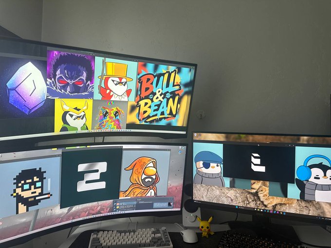 A multi-monitor gaming setup featuring various cartoon and game character wallpapers, including Angry Birds and a 'Bull & Bean' logo, with a Pikachu figure sitting on the desk.