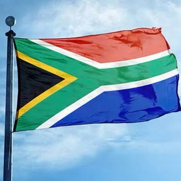 The South African flag waves against a blue sky, symbolizing the country's entry into cryptocurrency trading as FNB becomes the first in South Africa to offer customers 24/7 trading of BTC, ETH, XRP, SOL, and USDT.