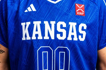 A close-up of a blue Kansas jersey featuring the Adidas logo, "KANSAS" lettering, the number 00, and a prominent XRP patch, tying into the celebratory XRP-themed post.