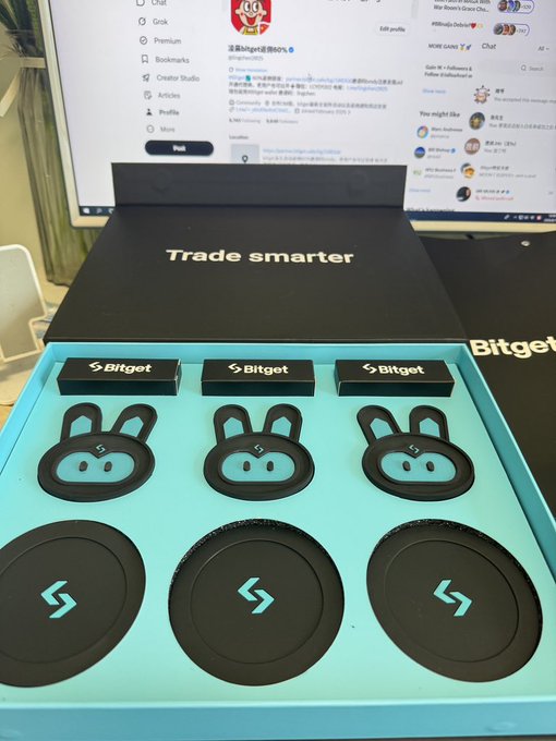 An open Bitget promotional gift box containing three black rabbit-shaped silicone items and three Bitget-branded circular items, with the lid reading 'Trade smarter'.