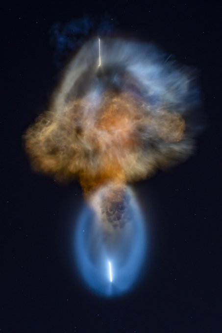 A colorful cosmic explosion in space, featuring orange and brown clouds of gas with bright blue jet-like streams emerging from a central sphere against a starry background.