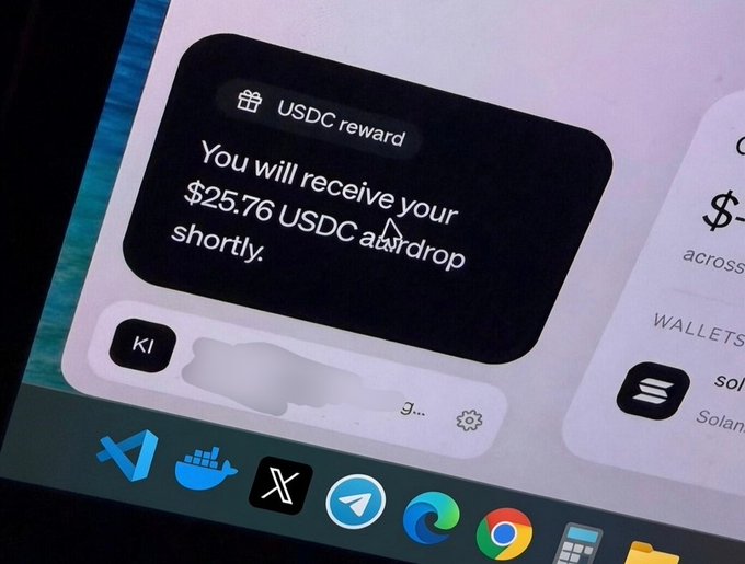 A notification on a computer screen displays "USDC reward - You will receive your $25.76 USDC airdrop shortly," with the Windows taskbar visible below showing icons for VS Code, Docker, X, Telegram, Edge, and Chrome, illustrating a user about to claim their PayBox rewards as mentioned in the post.