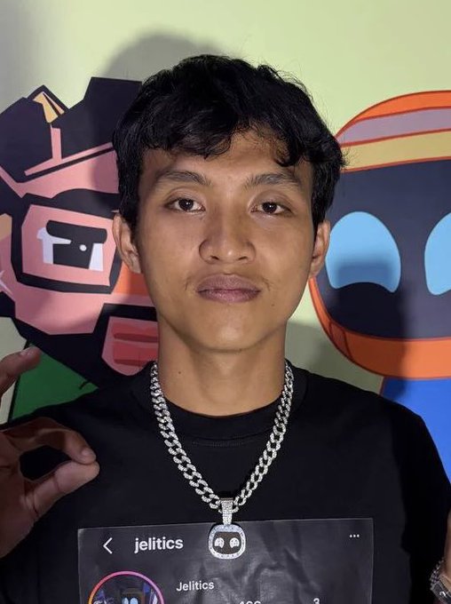 A young man wearing a black shirt and a silver chain necklace poses in front of colorful cartoon cutouts, with his Instagram profile "@jelitics" displayed at the bottom of the image, visually identifying him as the gambler-turned-trader referenced in the post about his $469,000 loss on the ticker $SI.