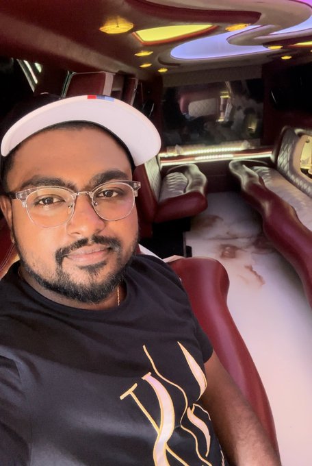 A man wearing glasses, a backwards cap, and a black shirt poses for a selfie inside a luxurious limousine with plush burgundy seating and ambient lighting. The opulent interior of the vehicle visually reinforces the post's aspirational tone about $POLY providing financial freedom and early retirement.